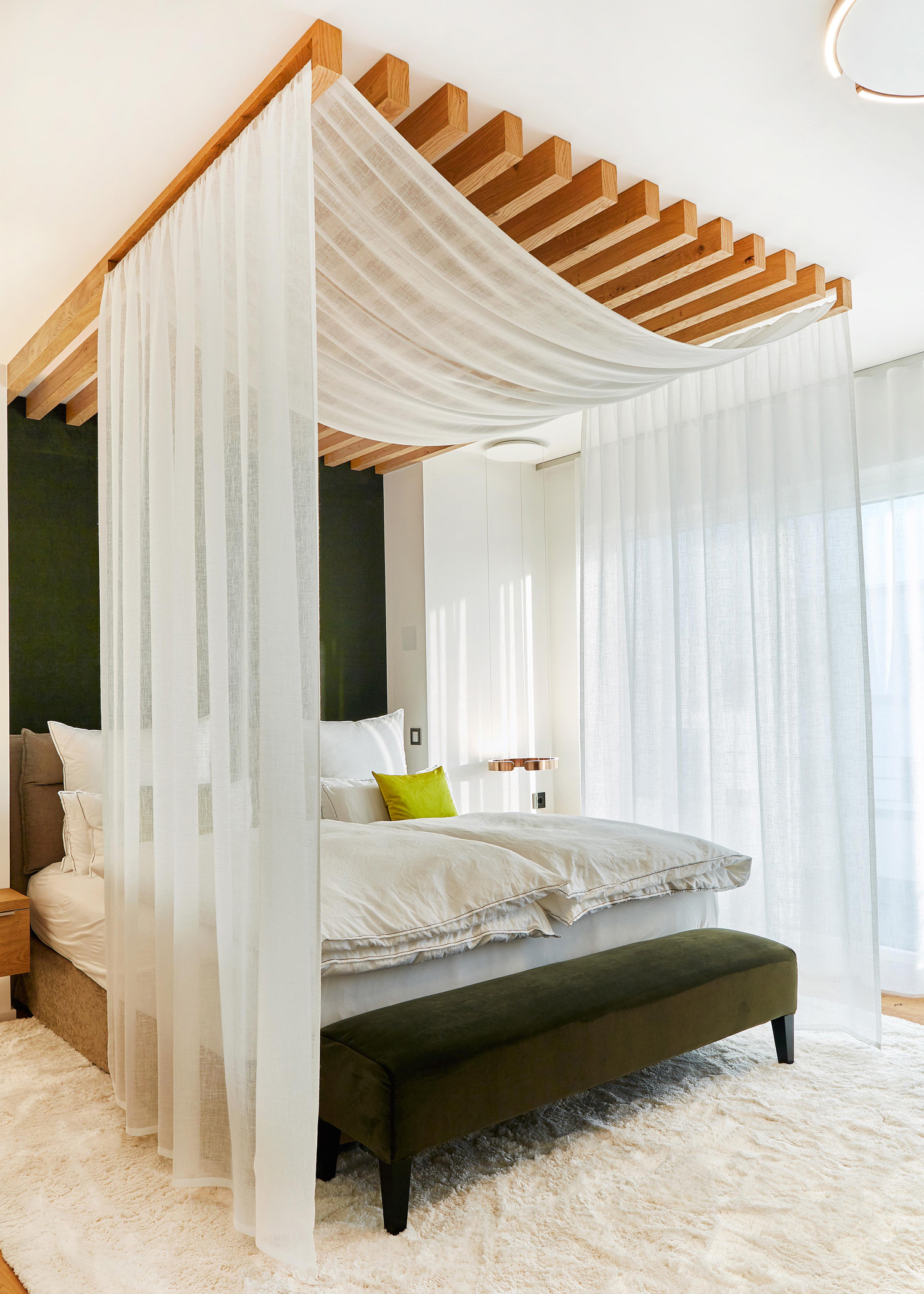 Foto: Elegantes Schlafzimmer mit modernem Himmelbett aus Holz, transparenten Vorhängen, weichem Teppich und warmen Naturmaterialien in ruhiger Atmosphäre.